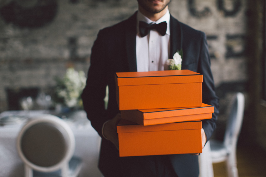 groom holding orange shoe boxes