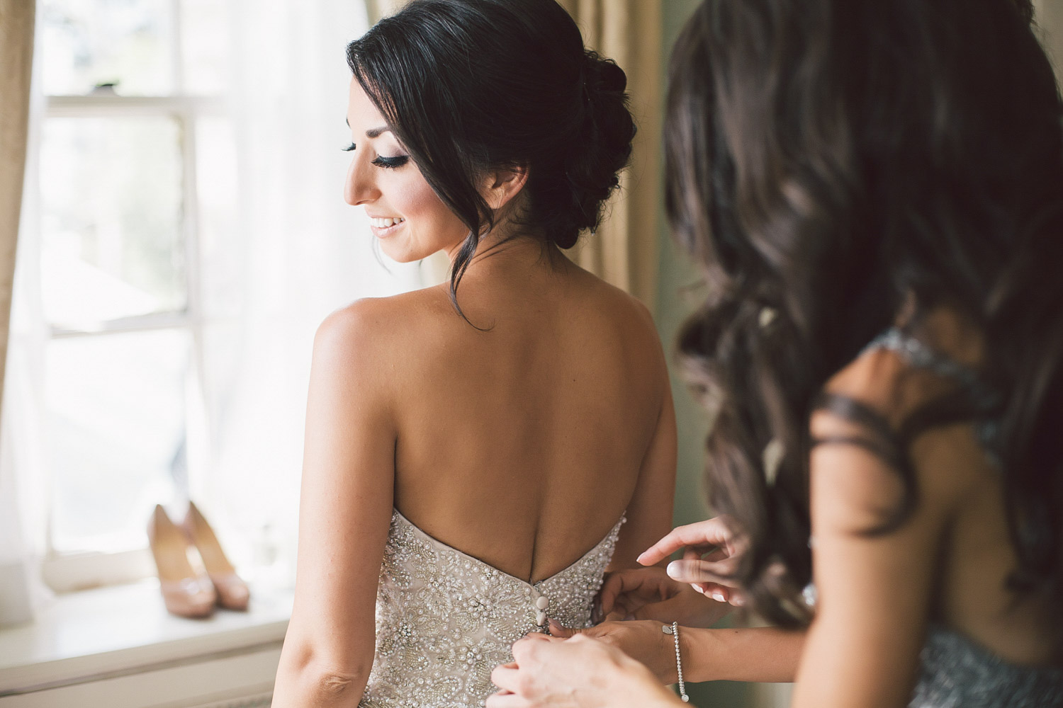 helping bride with the wedding dress