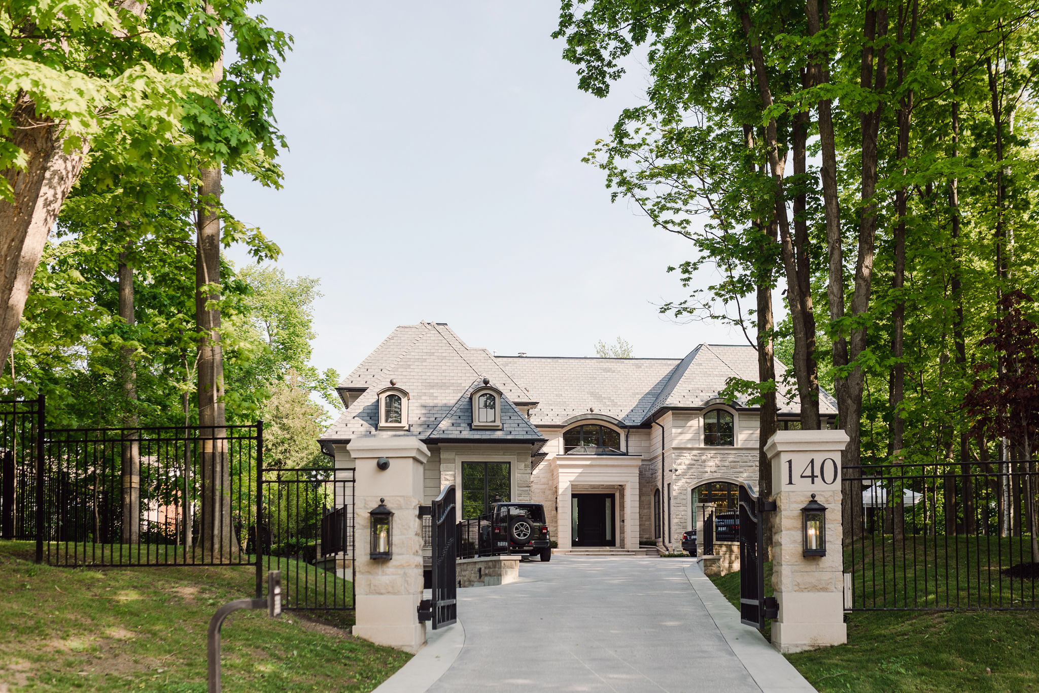 A picturesque driveway leading to a lavish mansion nestled in the enchanting woods, perfect for a wedding.