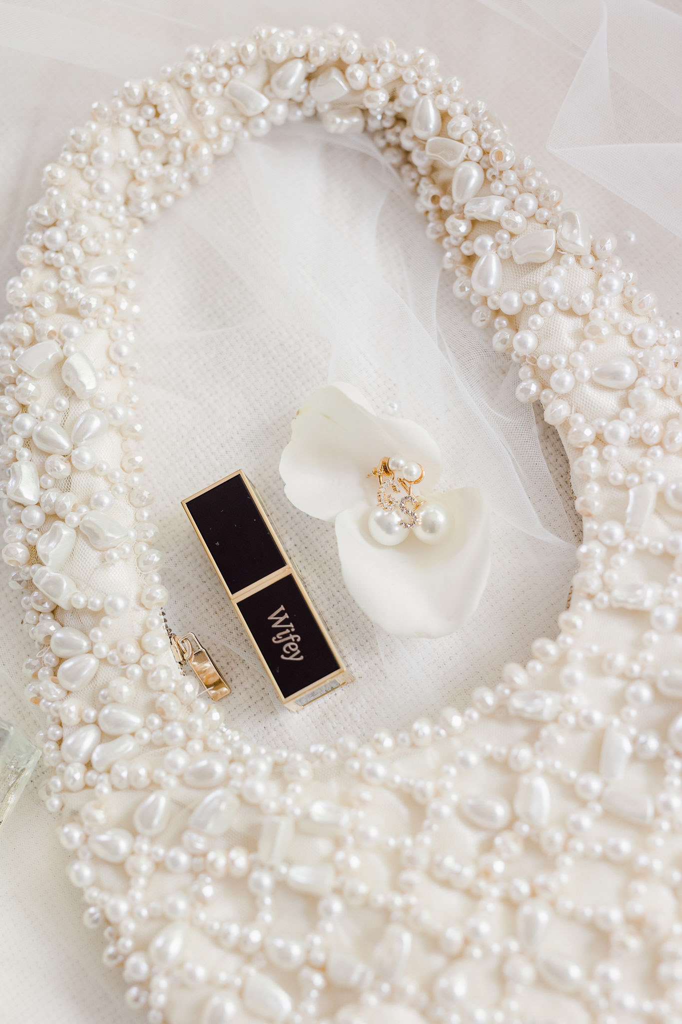 A white purse with pearls and jewelry on it.