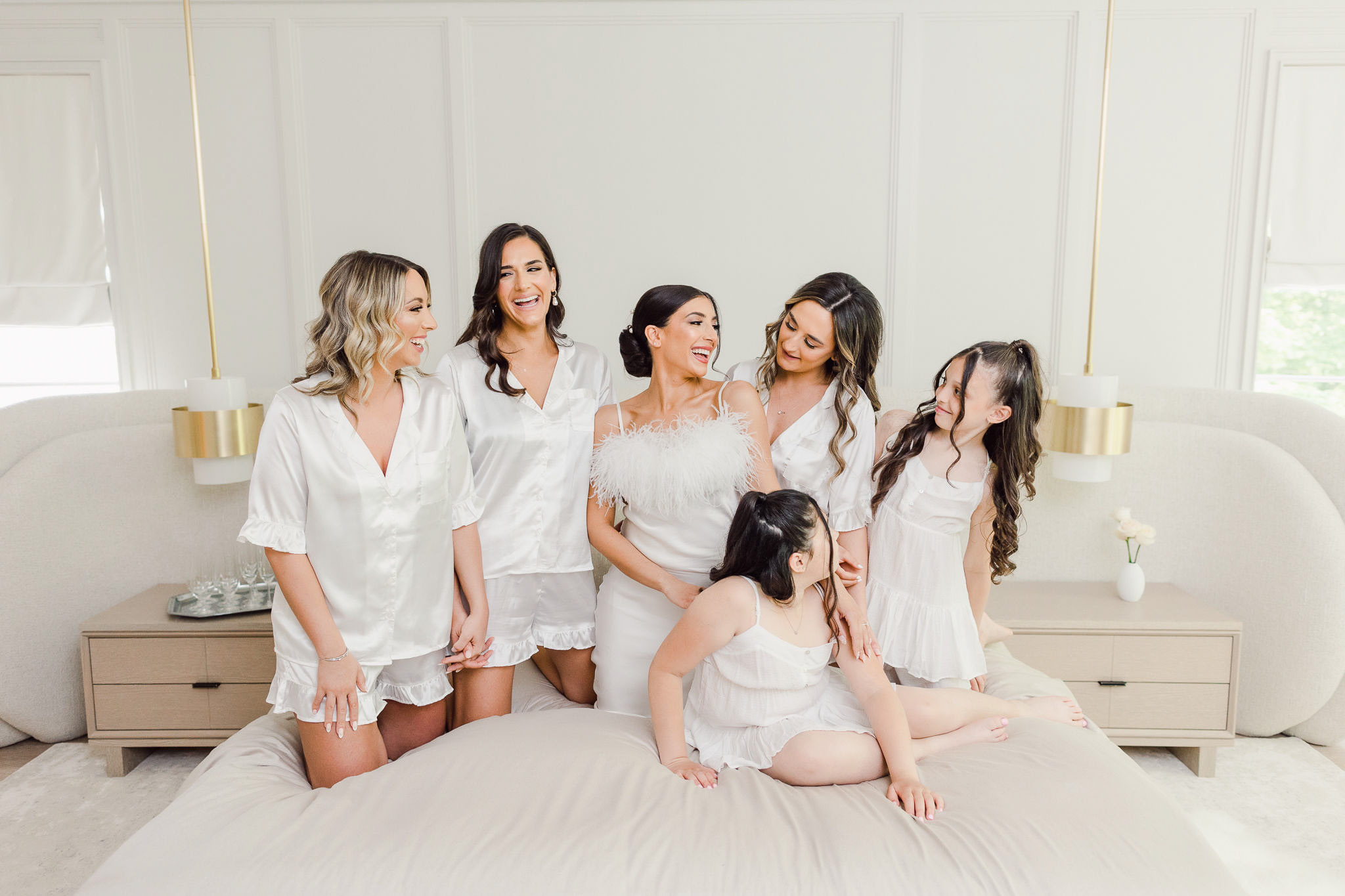 Bridesmaids posing for a photo on a bed.