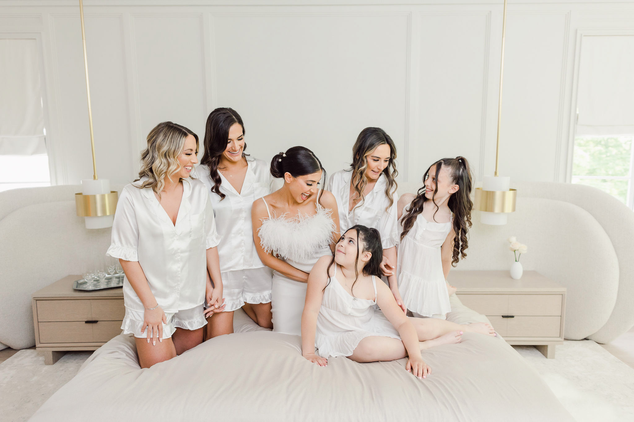 Bridesmaids posing for a photo on a bed.