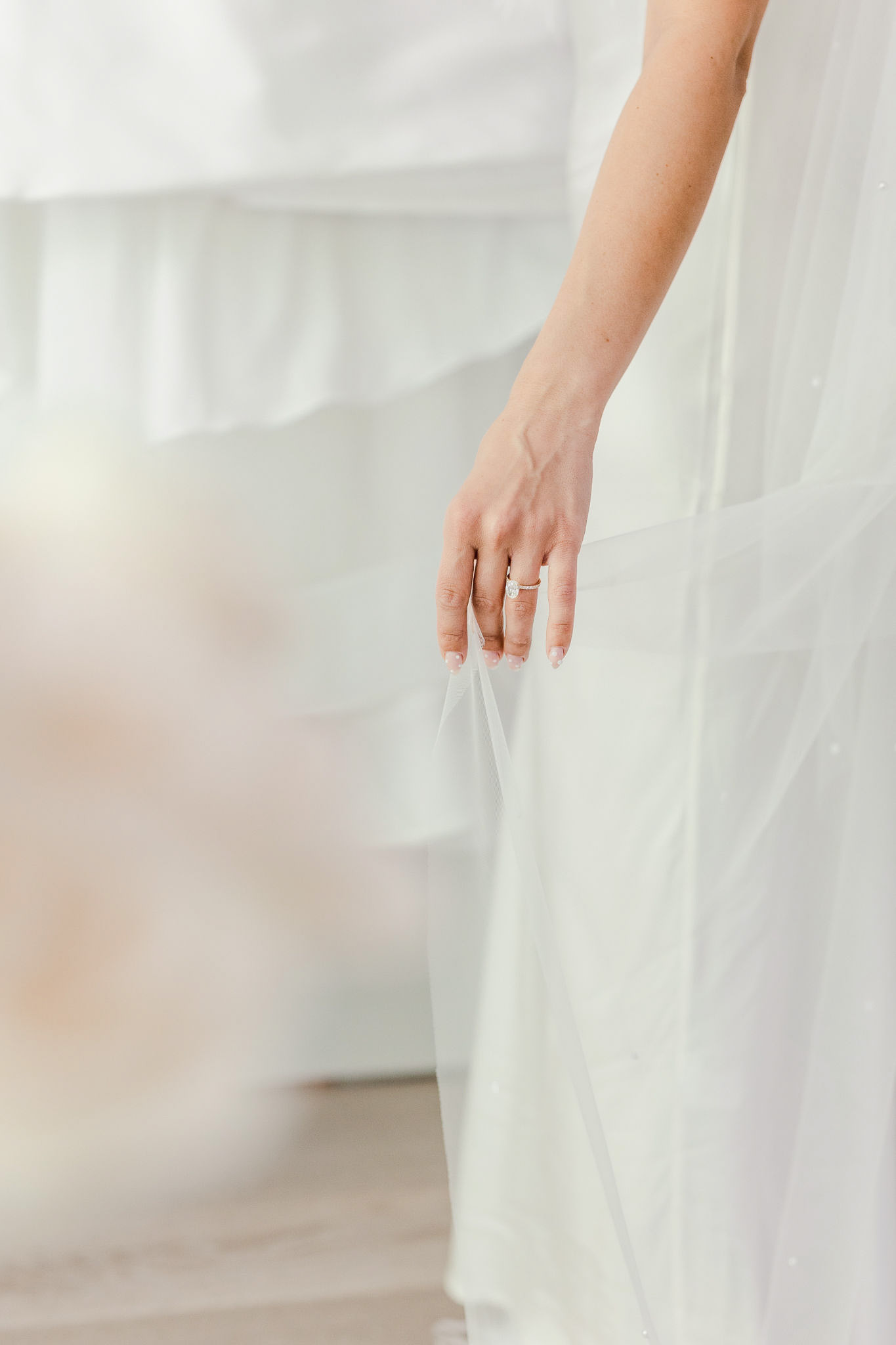A bride touching her wedding dress in a white room.