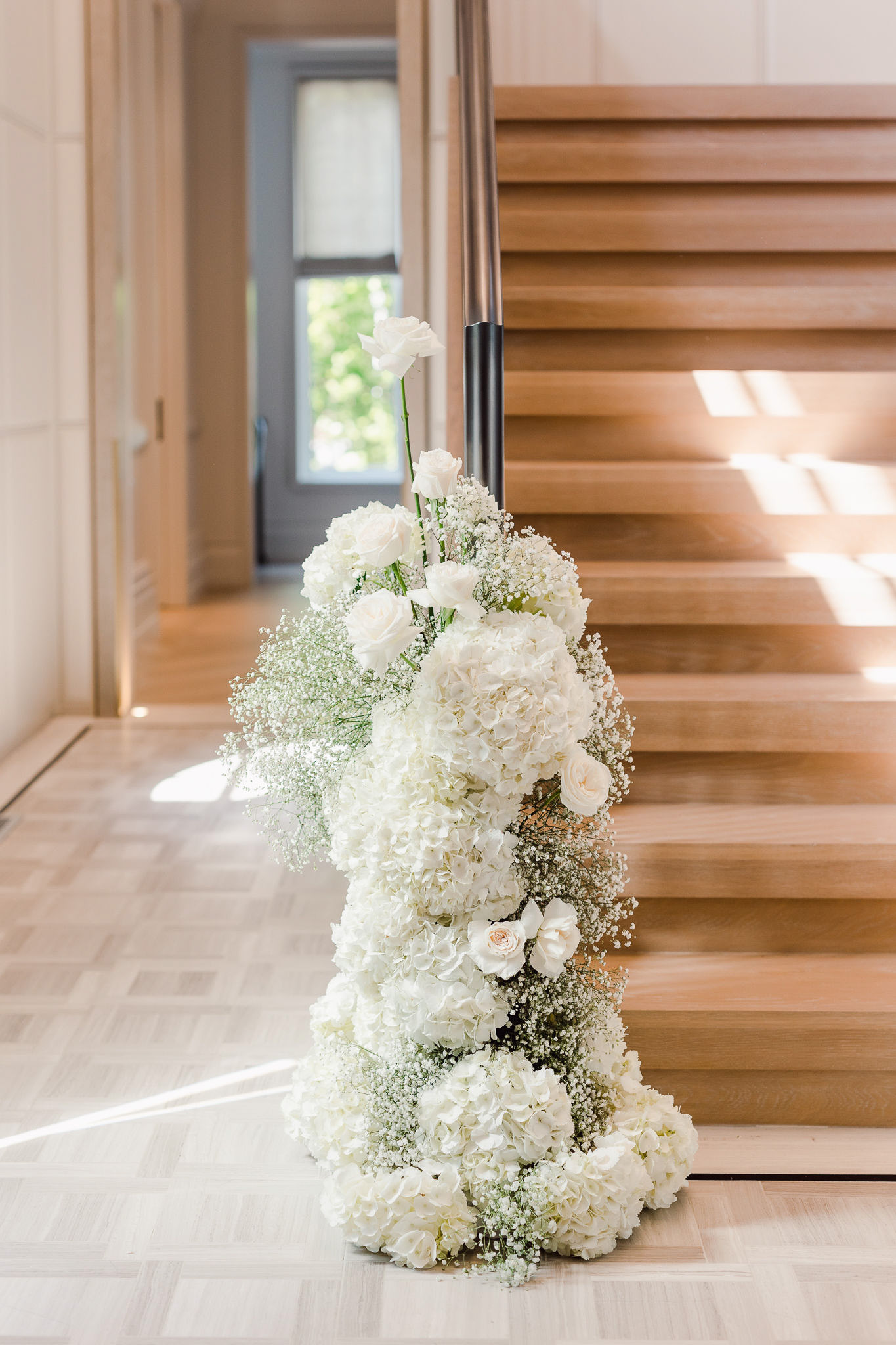 An arrangement of white flowers in front of a staircase.