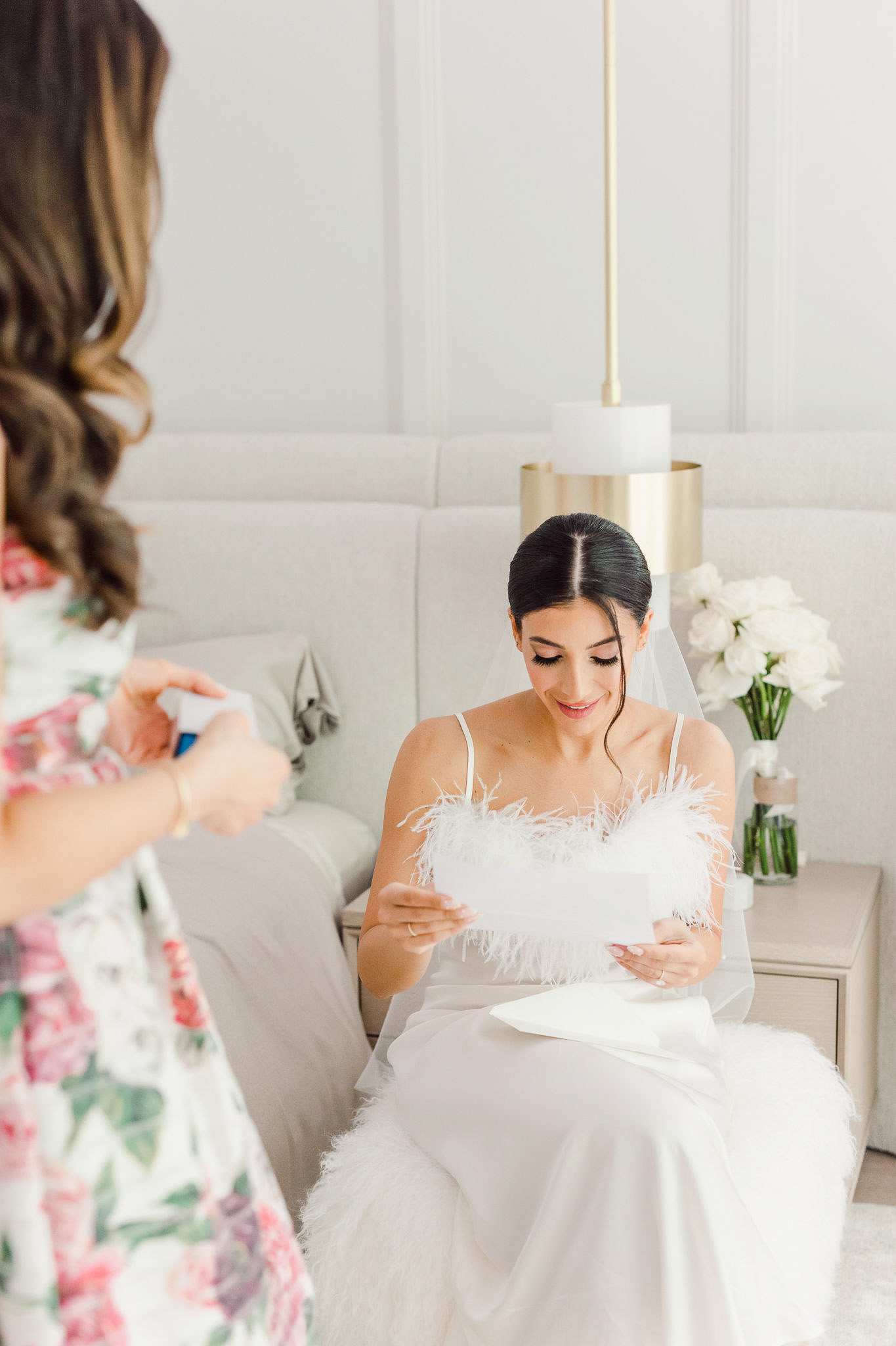 Two brides getting ready in a white bedroom.