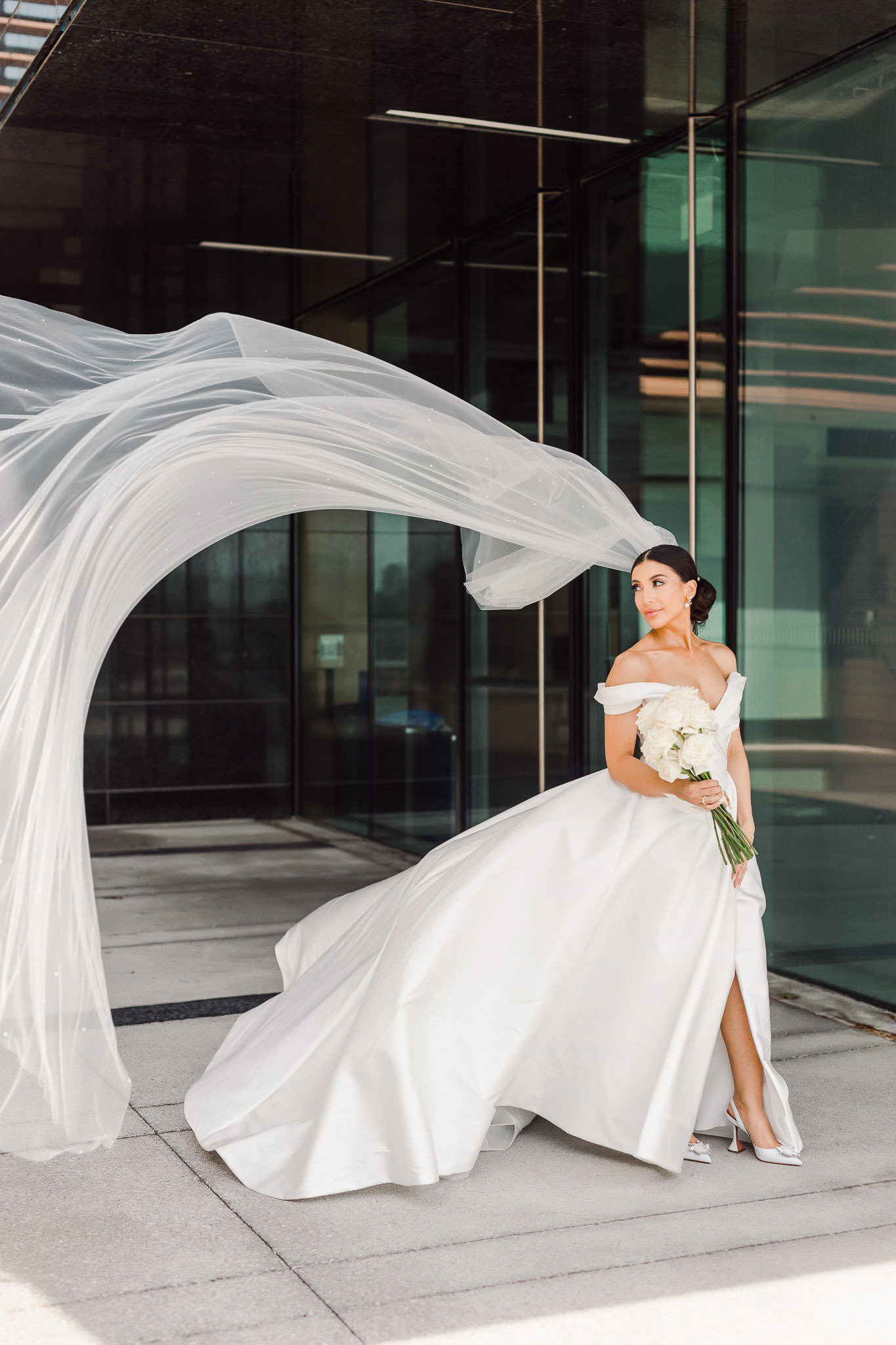 A bride with a veil caught in the wind in front of Vaughan City Hall