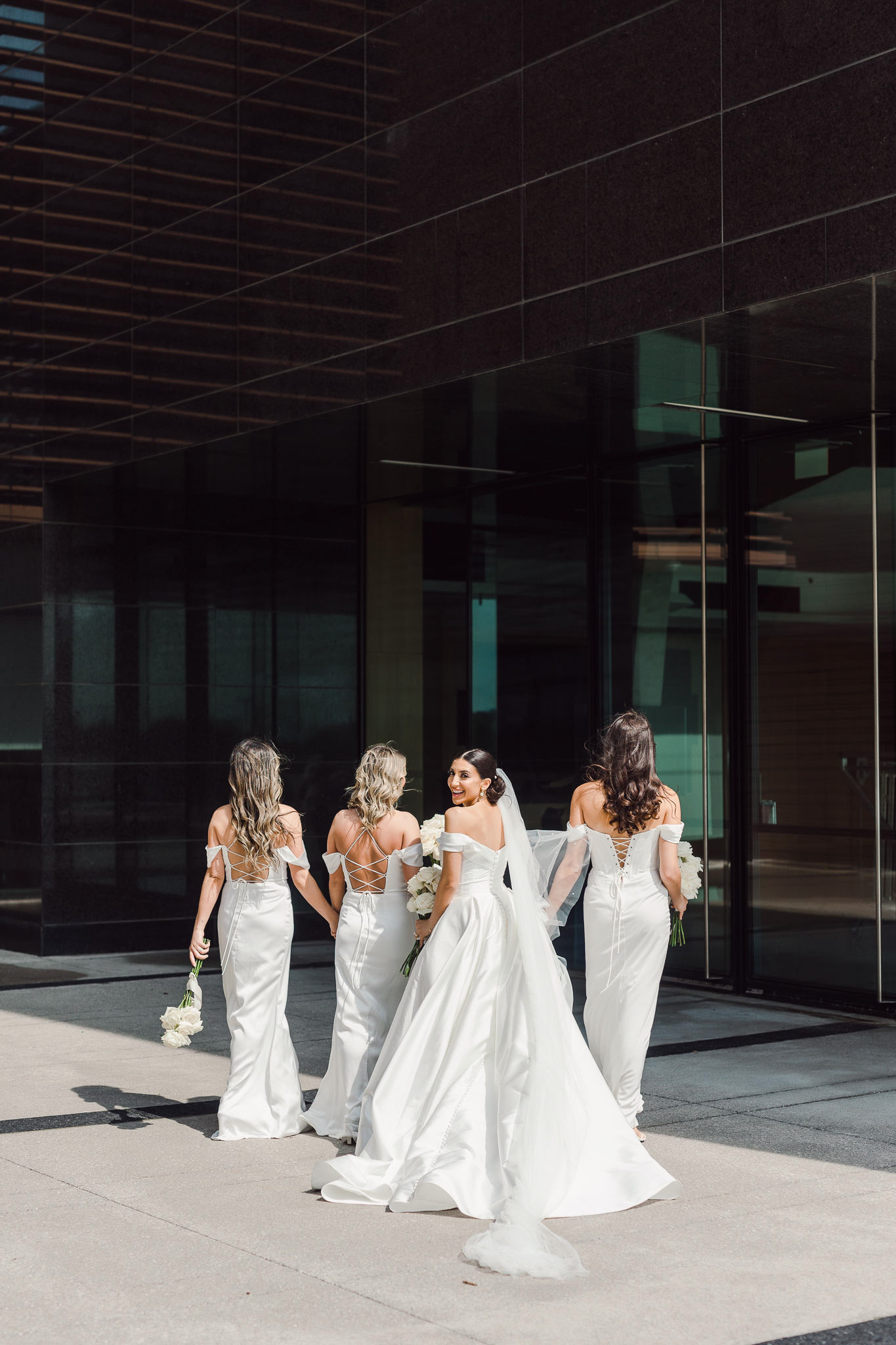 A bride and her bridesmaids walk in front of Vaughan City Hall.