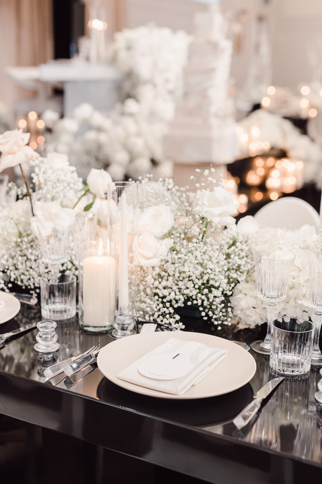 A black and white table setting with candles and baby's breath.
