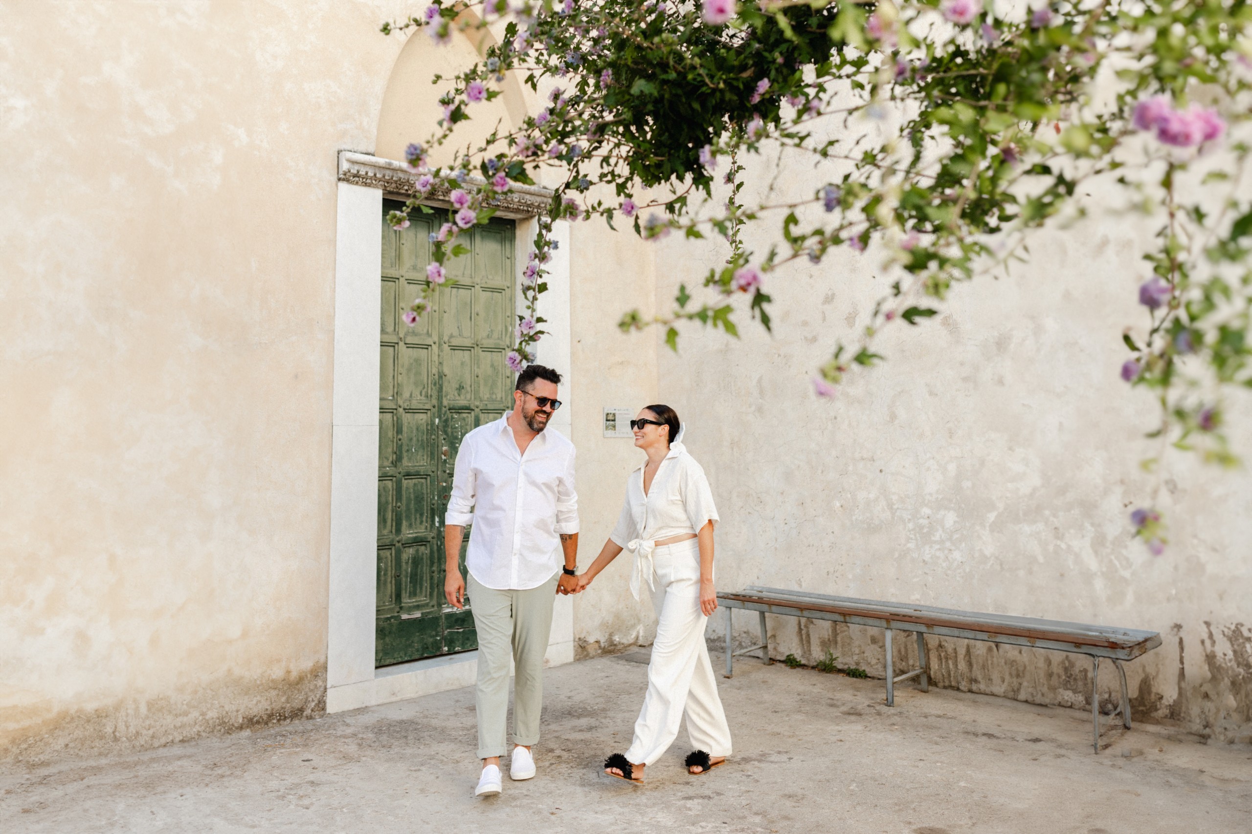 An engaged couple holding hands in front of an old building during their Italy engagement session.