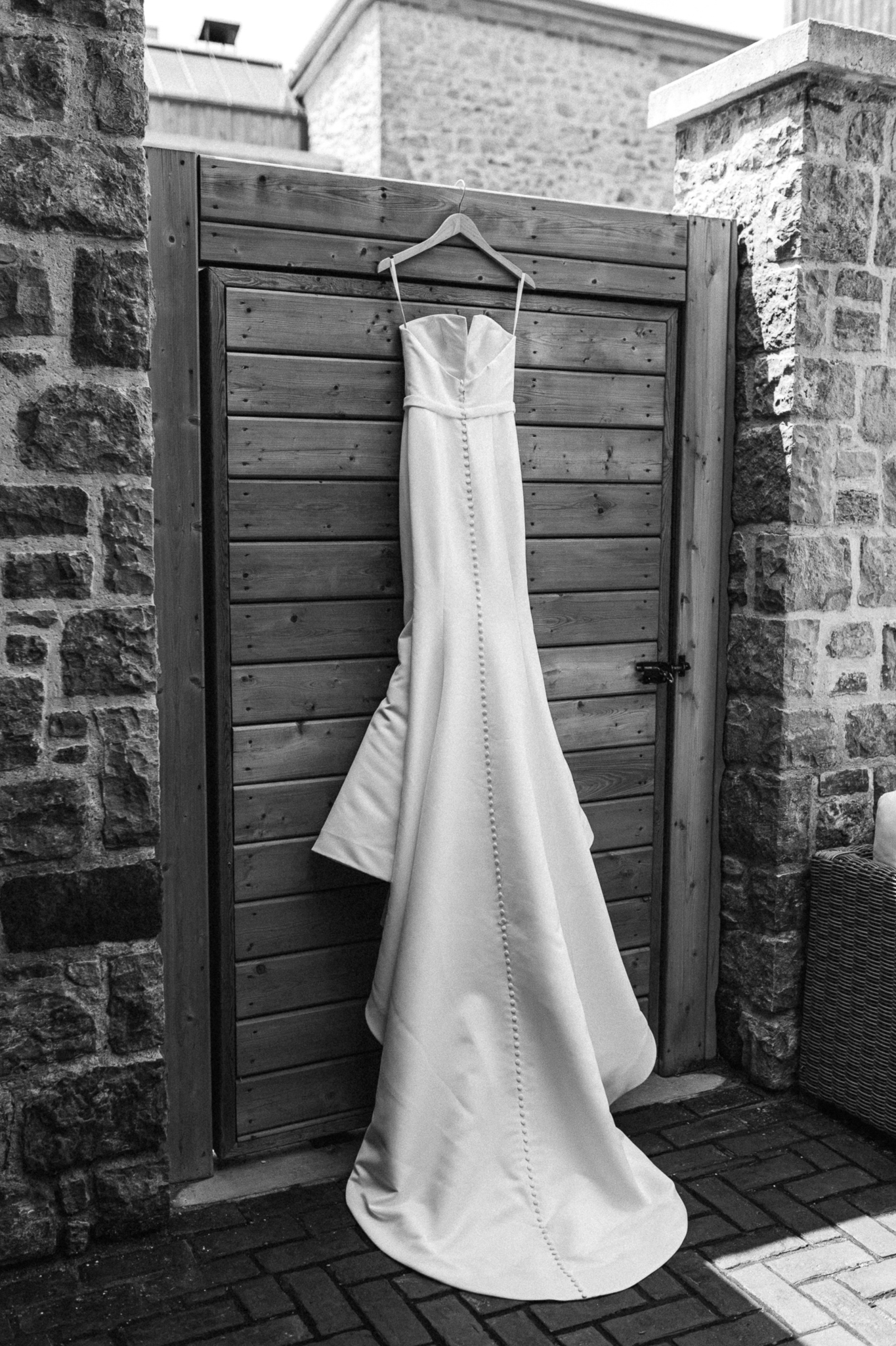 A wedding dress gracefully adorns a rustic wooden door.