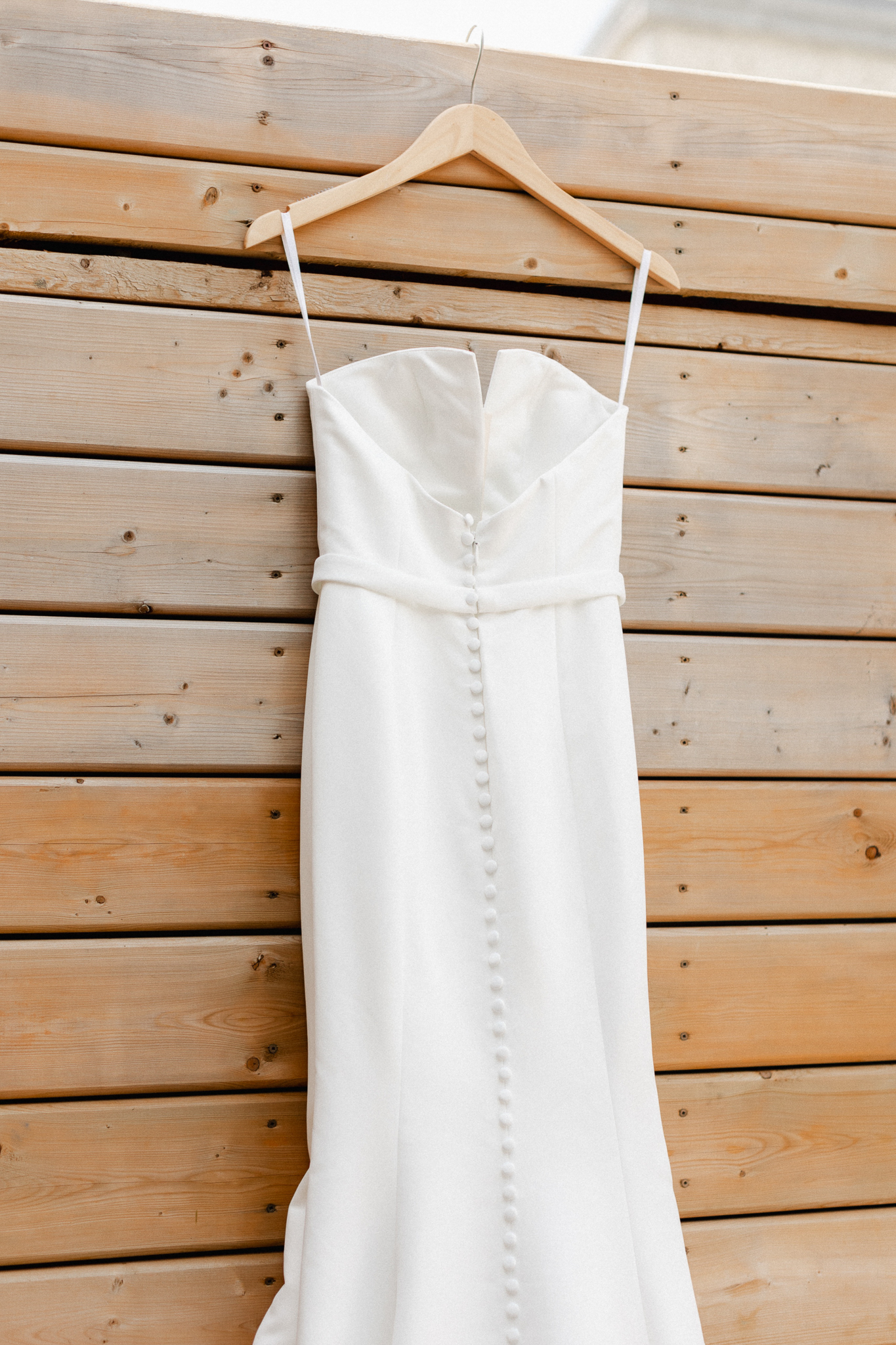 A wedding dress gracefully adorns a rustic wooden door, closeup.