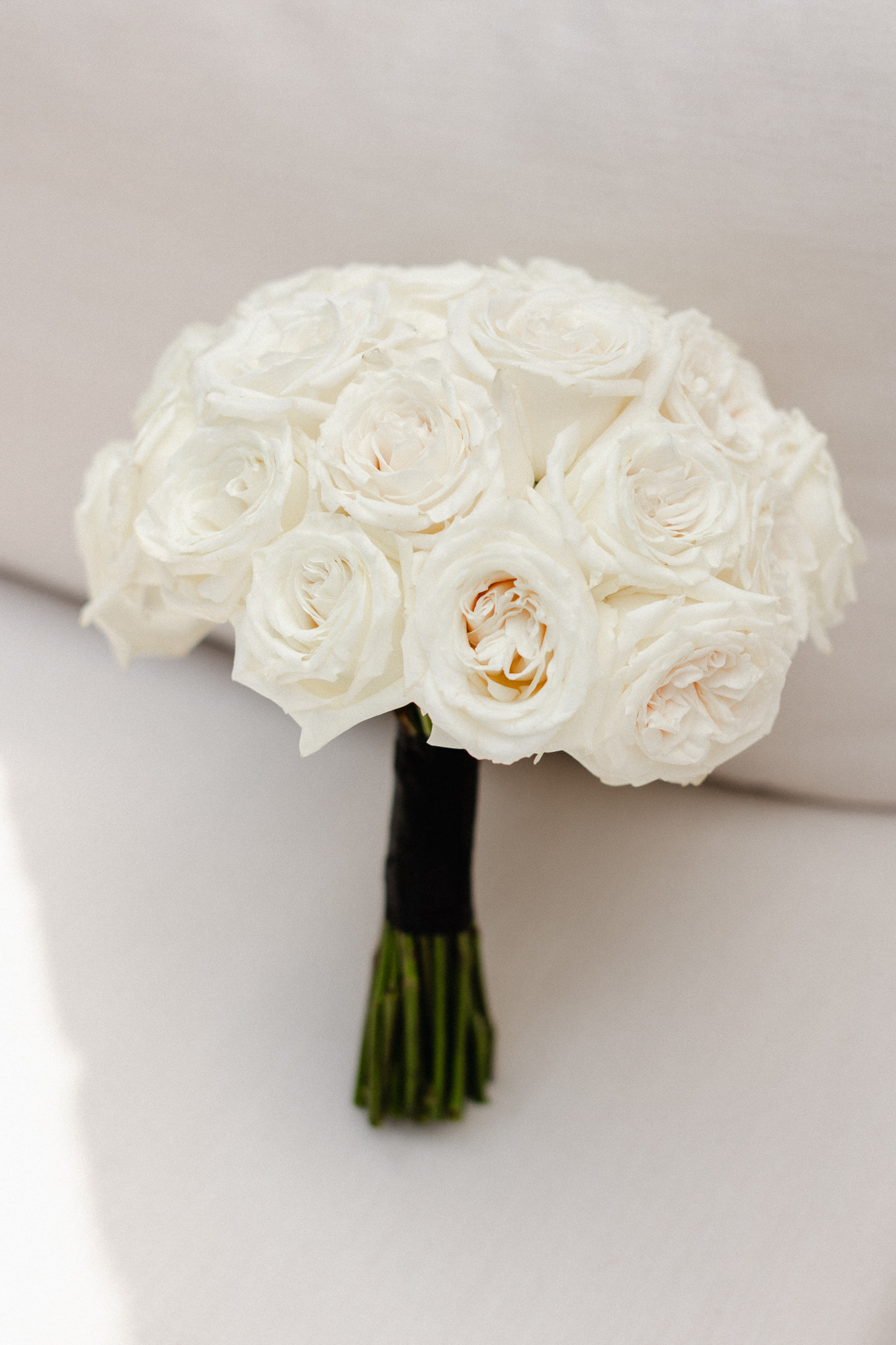 A beautiful arrangement of white roses elegantly placed on a couch, serving as a bride's bouquet.