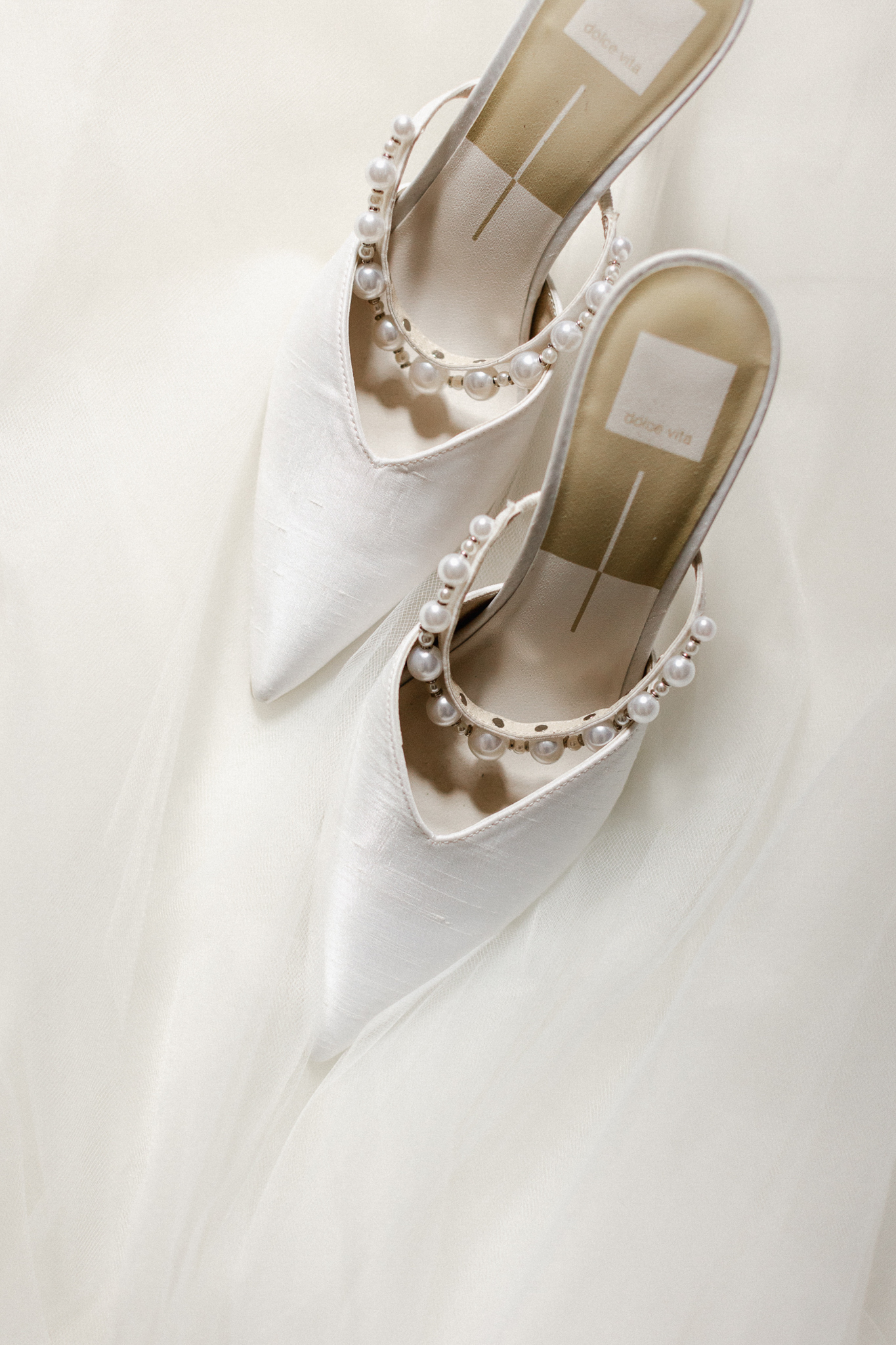 A pair of elegant white wedding shoes adorned with delicate pearls by Dolce Vita