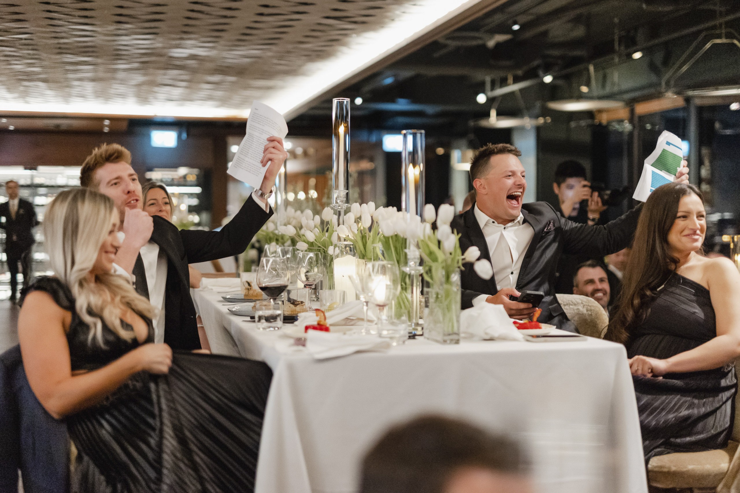 Groomsmen cheering during bride and groom wedding speech at reception.