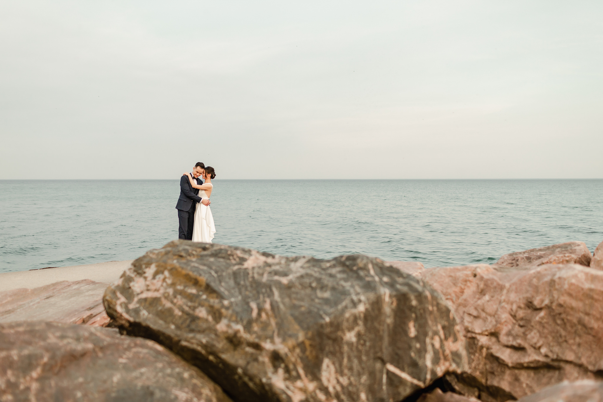 Wedding photographer capturing a couple's engagement session pose by lakefront.
