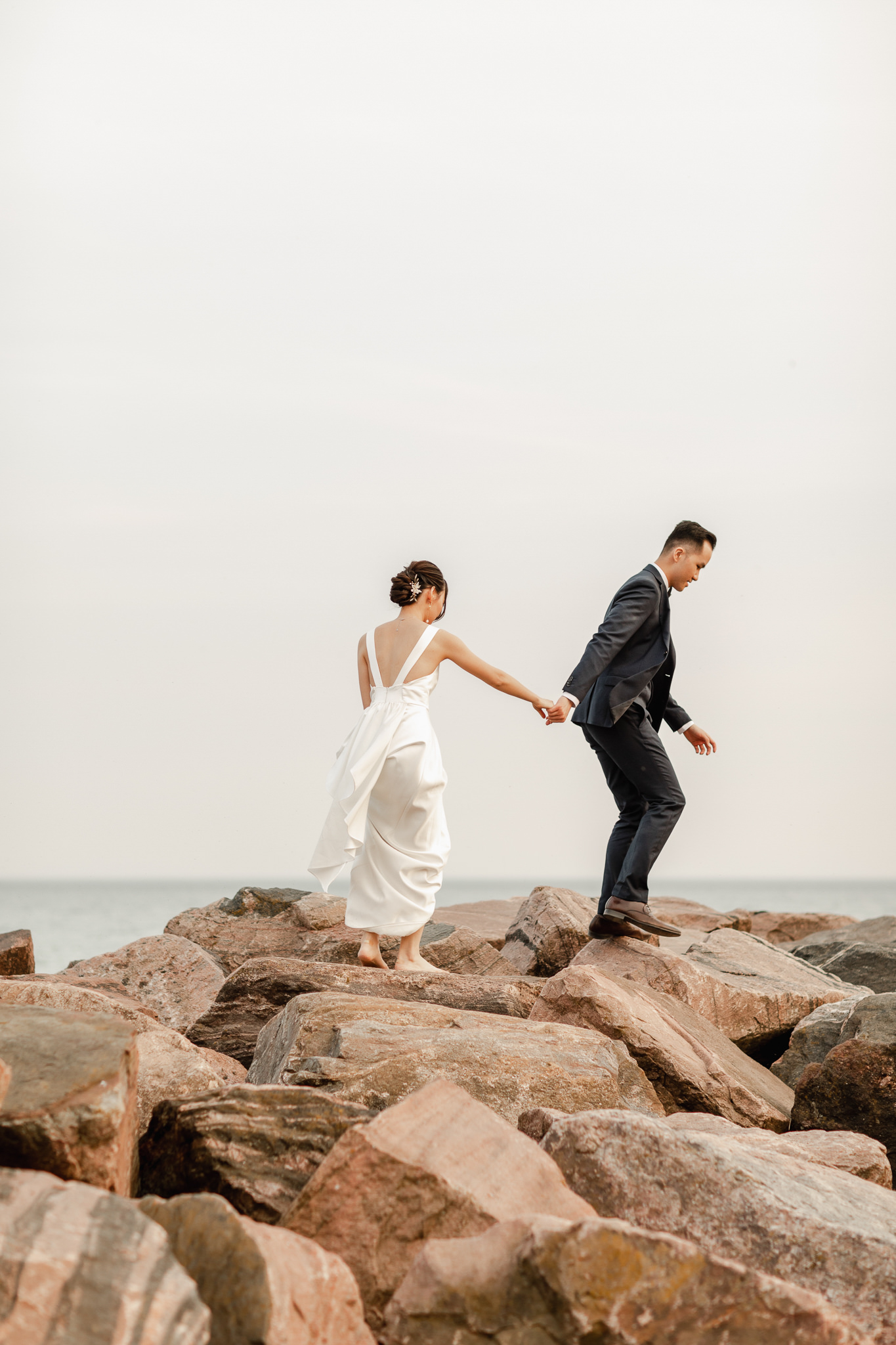 Wedding photographer capturing a couple's engagement session pose by lakefront.