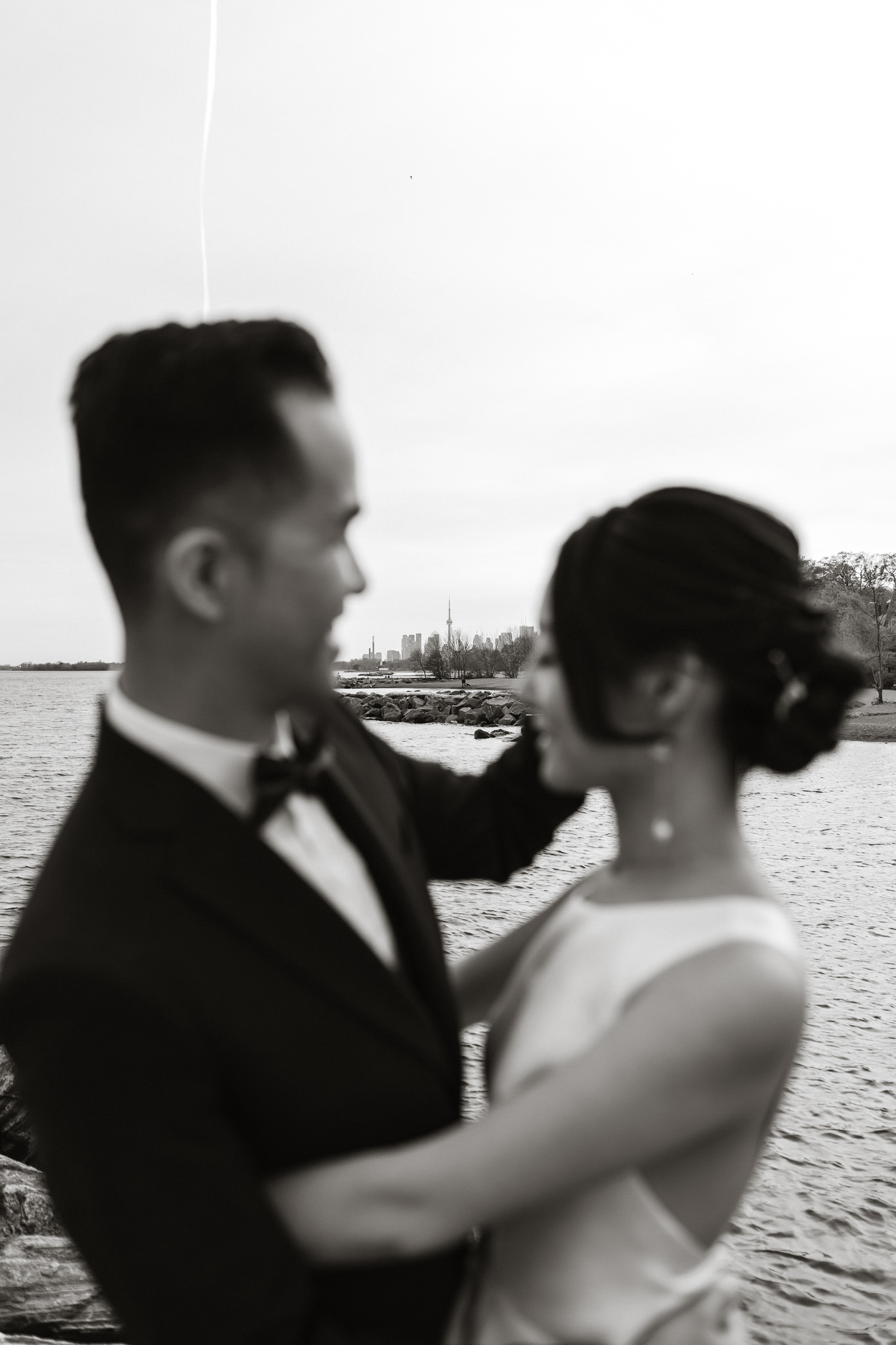 Wedding photographer capturing a couple's engagement session pose by lakefront.
