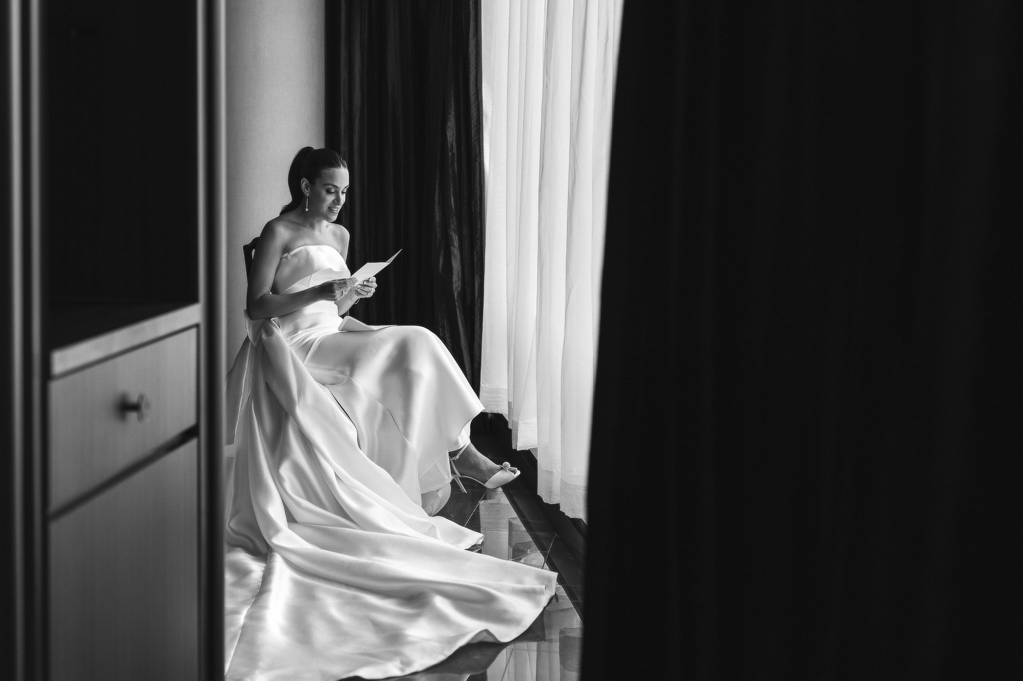 Bride reading card from the groom in hotel suite.