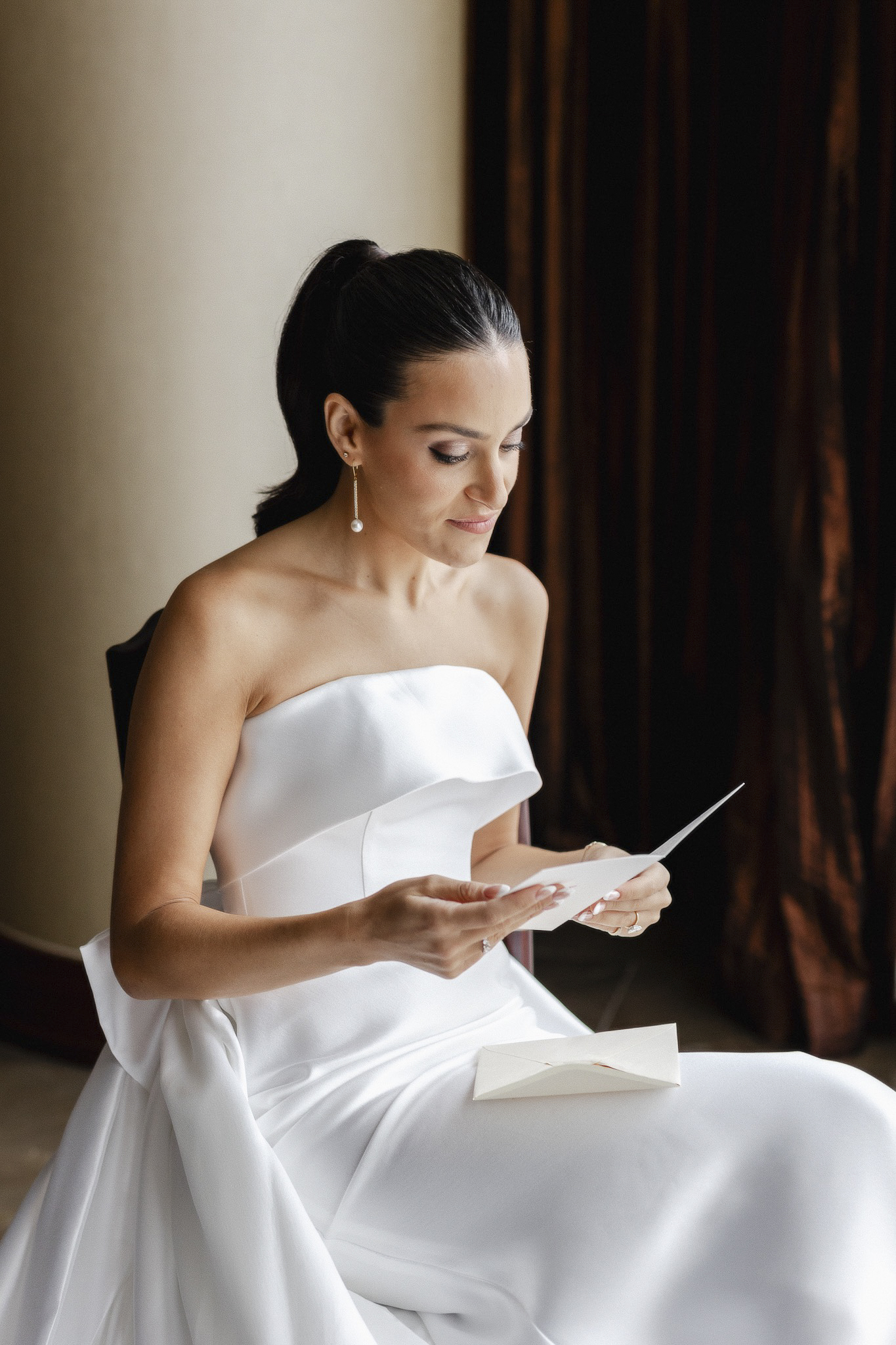 Bride reading card from the groom in hotel suite.
