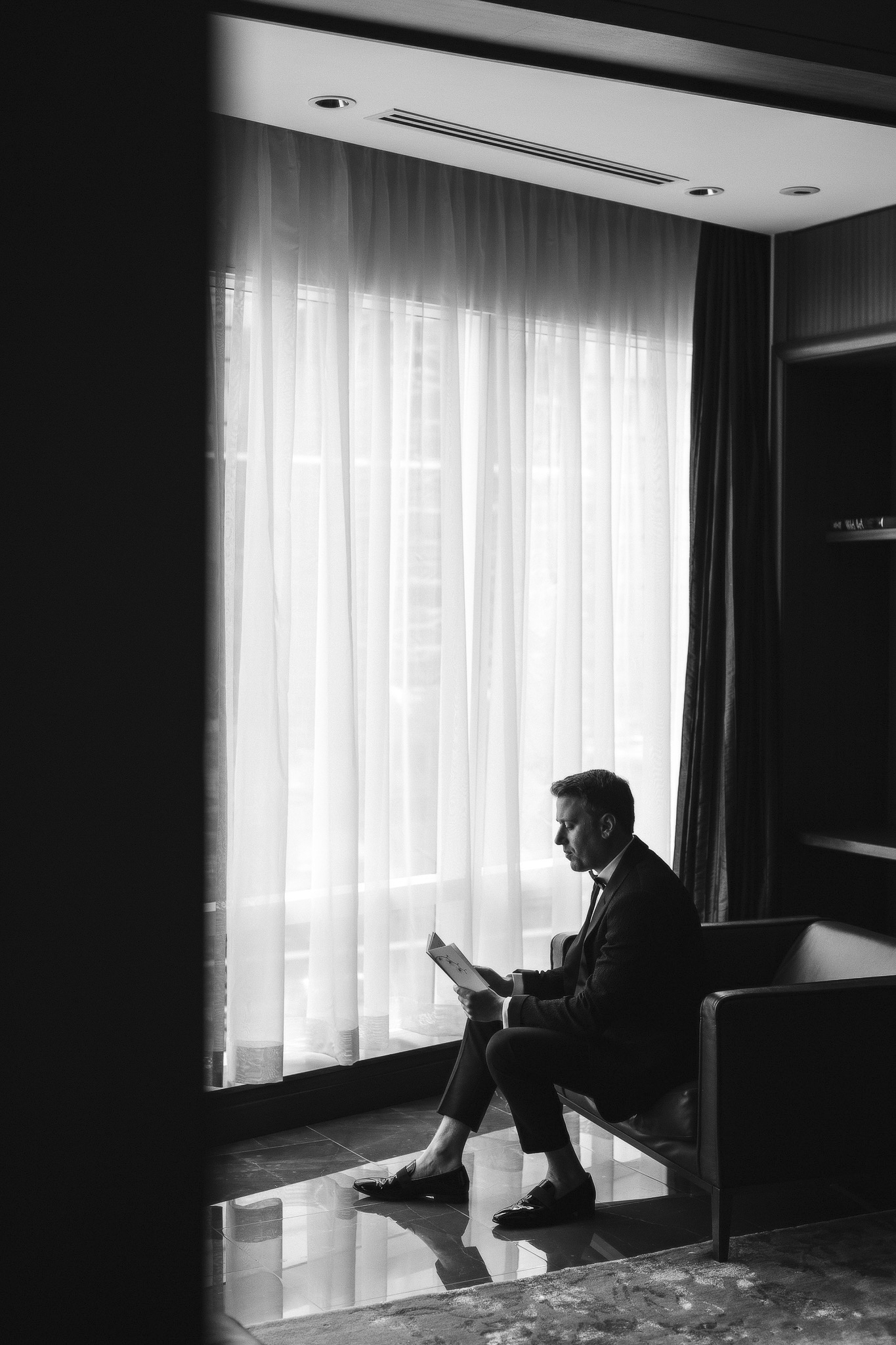 Groom reading card from bride in hotel suite.