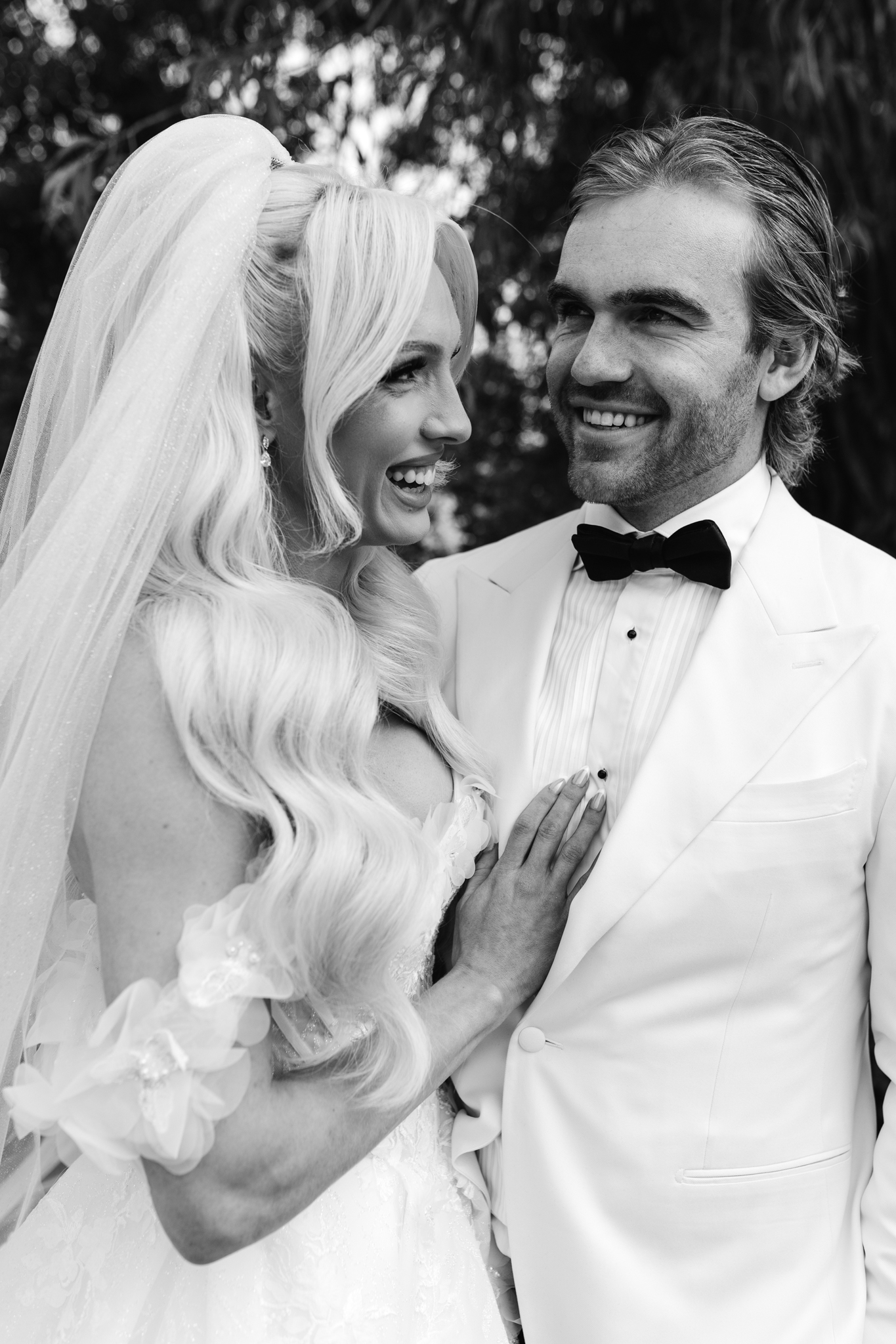 Candid black and white portrait of a bride and groom laughing together in an unposed, intimate moment during their wedding day
