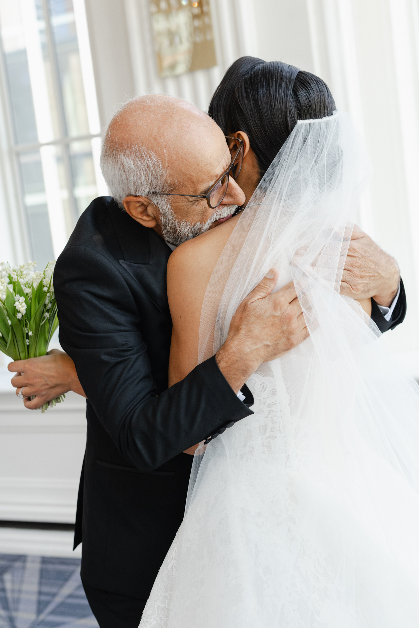 Father embracing his bride daughter in a tender, emotional moment before the ceremony, captured in a candid wedding photograph