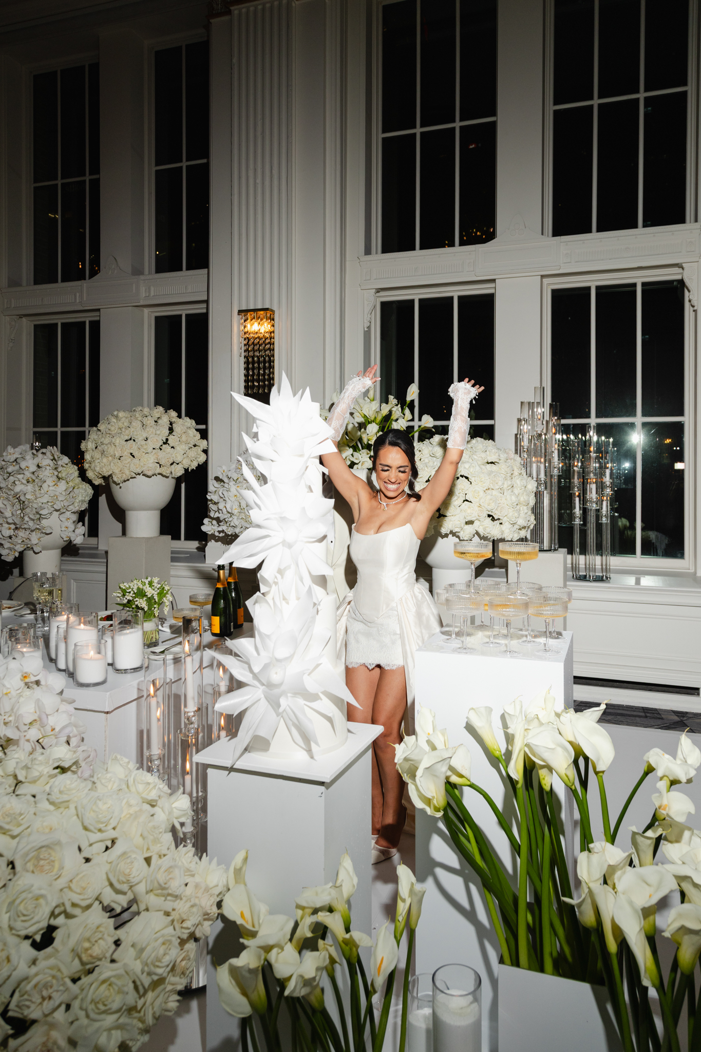Bride dancing on a table surrounded by white florals during an elegant wedding reception, captured in a bold, editorial, fashion-inspired style in Crystall Ballroom Omni King Edward Hotel in Toronto